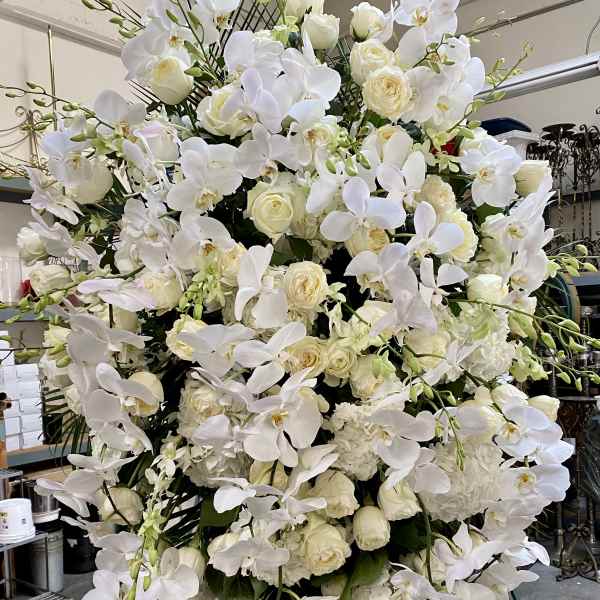 Large white floral standing arrangement with orchids and roses