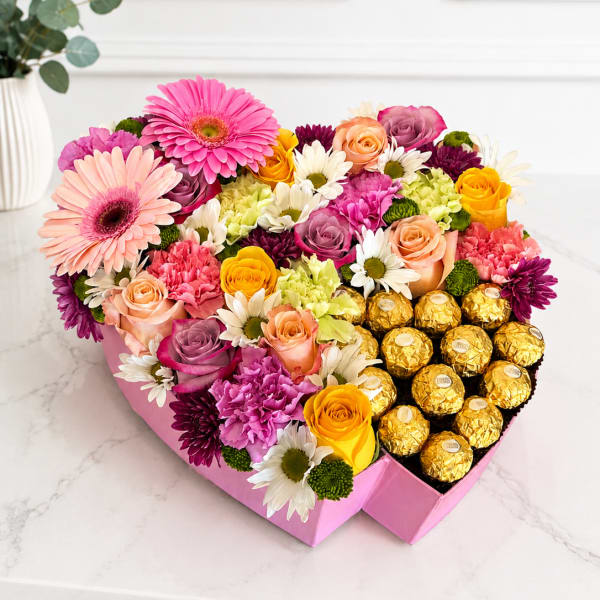 Heart-shaped box of mixed flowers and gold-wrapped chocolates