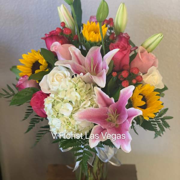 Bouquet of pink lilies, roses, hydrangea, and sunflowers in a glass vase