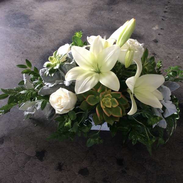 White lilies and roses arranged with succulents and greenery