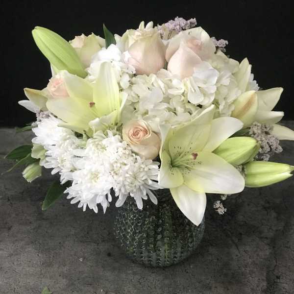 White lilies and pale roses in a textured glass vase