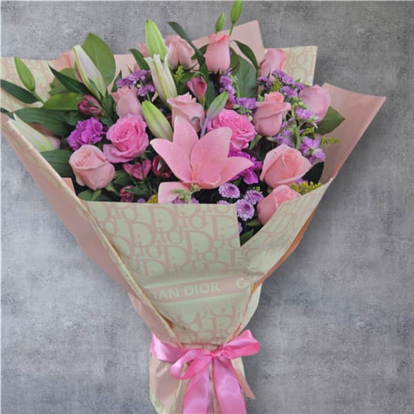 Pink rose and lily bouquet wrapped in patterned paper with a pink ribbon