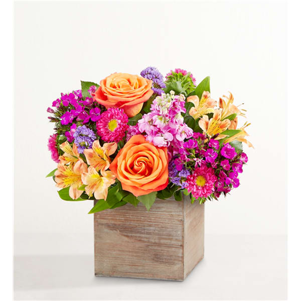 Bright mixed bouquet in a wooden box with orange roses and pink flowers