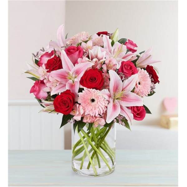 Pink lilies and red roses arranged in a clear glass vase