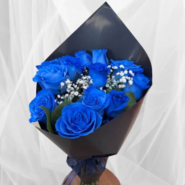 Bouquet of bright blue roses with baby's breath in dark wrapping