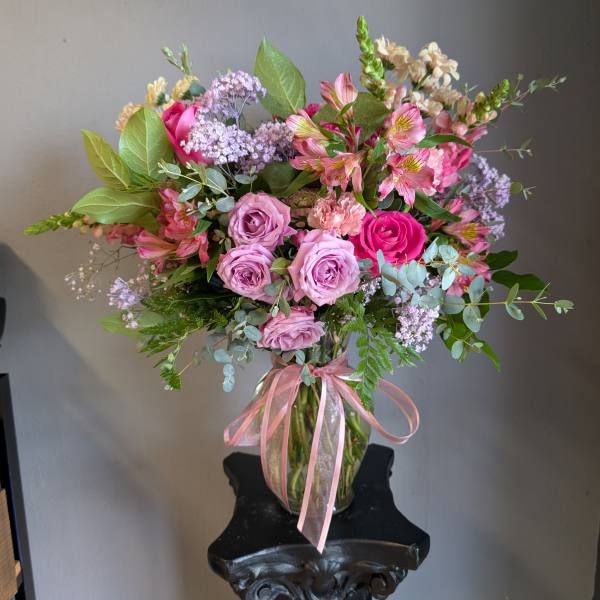 Pink and lavender bouquet in a glass vase with a pink ribbon