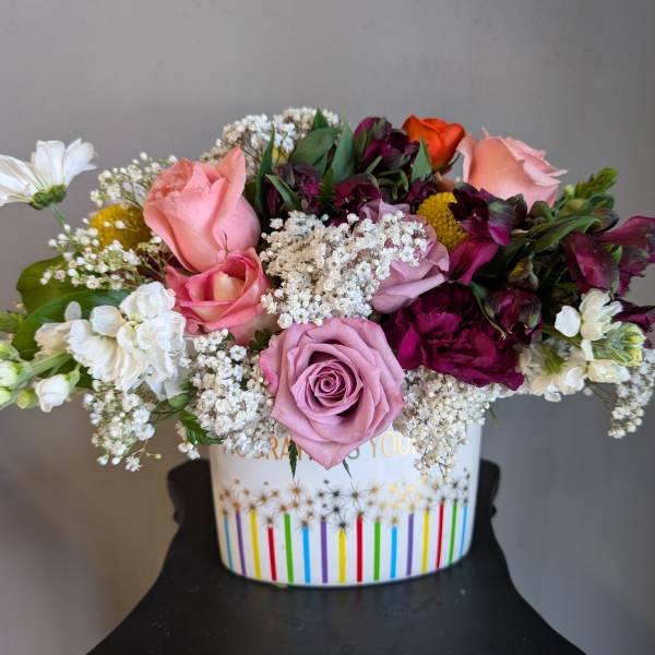 Mixed bouquet of pink, white, and purple flowers in a decorated container