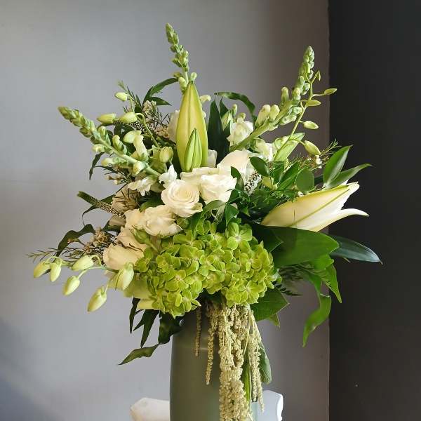 White and green floral arrangement in a tall vase