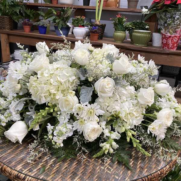 Large white floral arrangement with roses, hydrangeas, and daisies