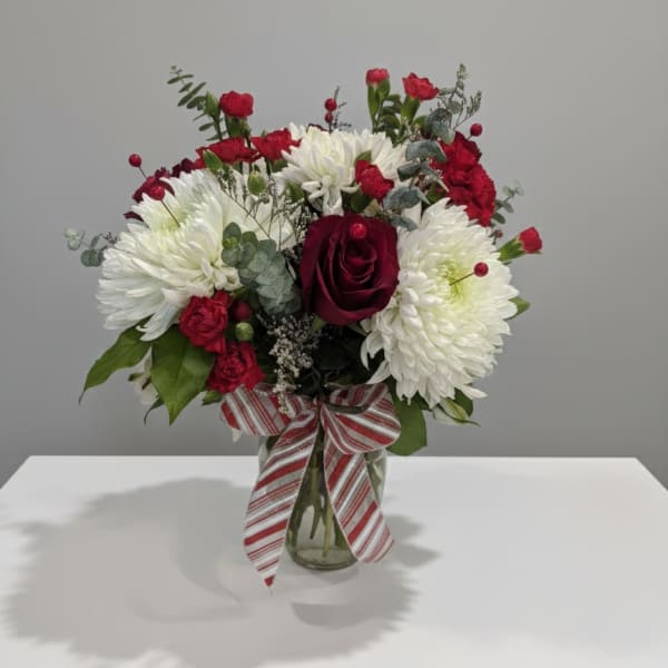 Red and white bouquet in a glass vase with a striped ribbon