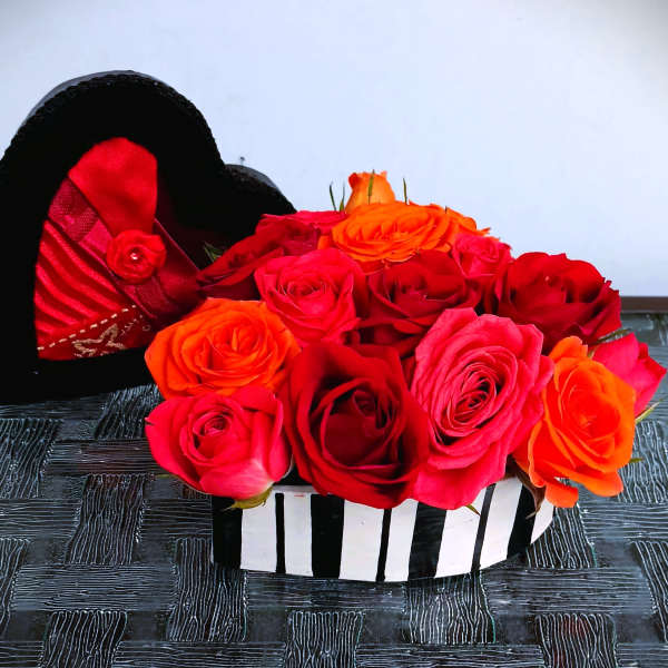 Heart-shaped box filled with red, pink, and orange roses