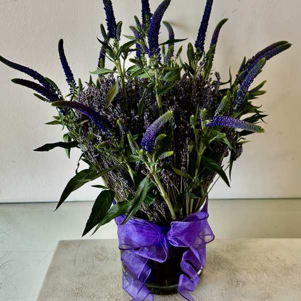 Purple flower arrangement in a glass vase with a ribbon bow