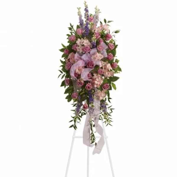 Tall pink and lavender standing spray with roses and accent blooms on a white easel.