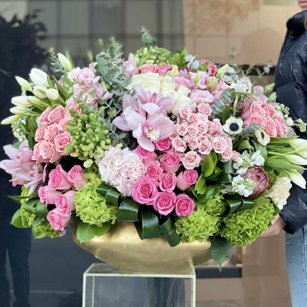 Large pink and white floral arrangement in a gold vase