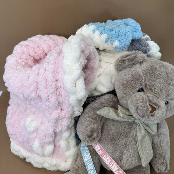Plush teddy bear with pastel blankets in a box