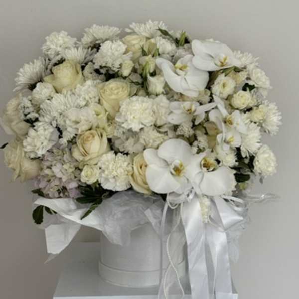 White floral arrangement in a round hatbox with ribbon