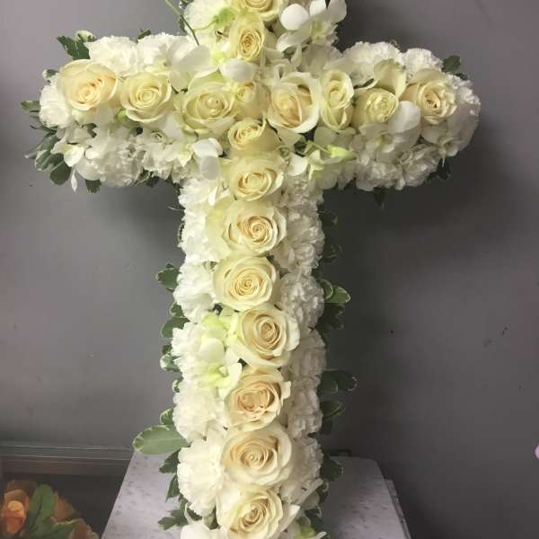 White floral cross with cream roses and white blooms