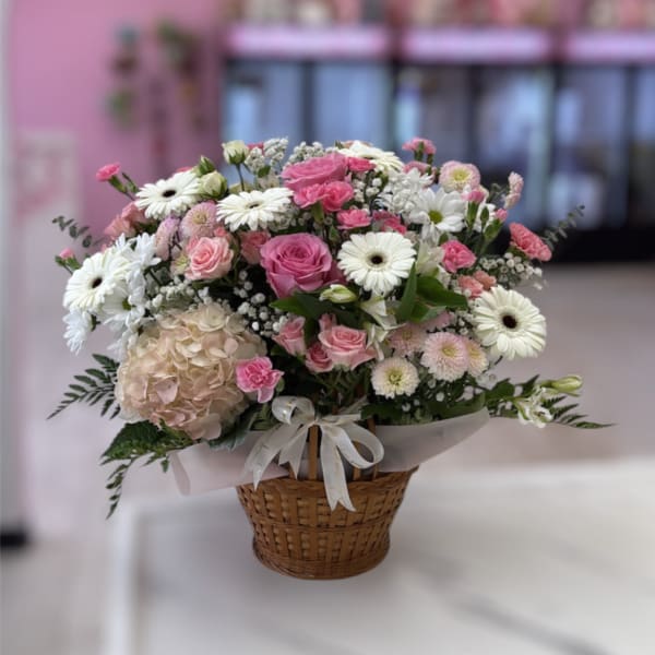Pink and white mixed flower basket arrangement in a wicker basket