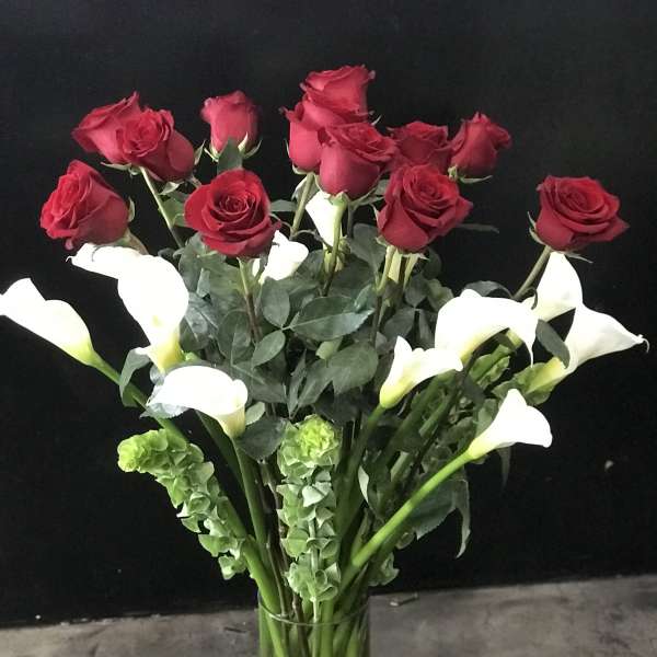 Red roses and white calla lilies in a clear glass vase