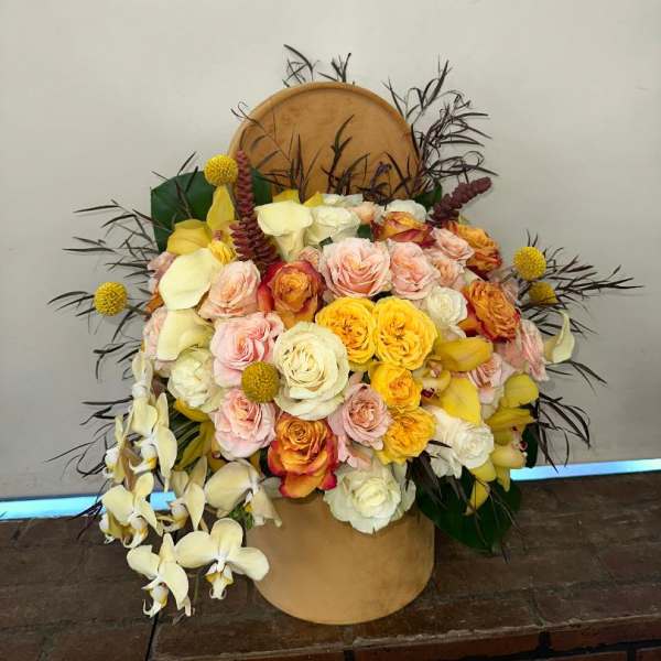 Large bouquet of roses and orchids in a tan hatbox