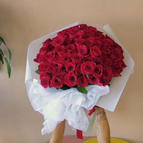 Large bouquet of red roses wrapped in white paper with a ribbon