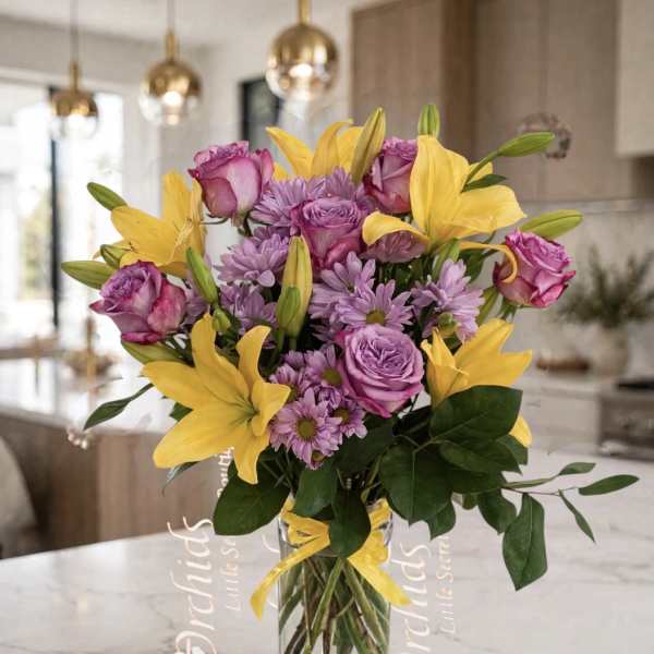Bouquet of yellow lilies, purple roses, and lavender daisies in a glass vase