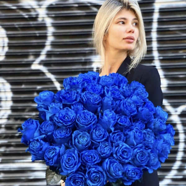 Woman holding a large bouquet of vivid blue roses
