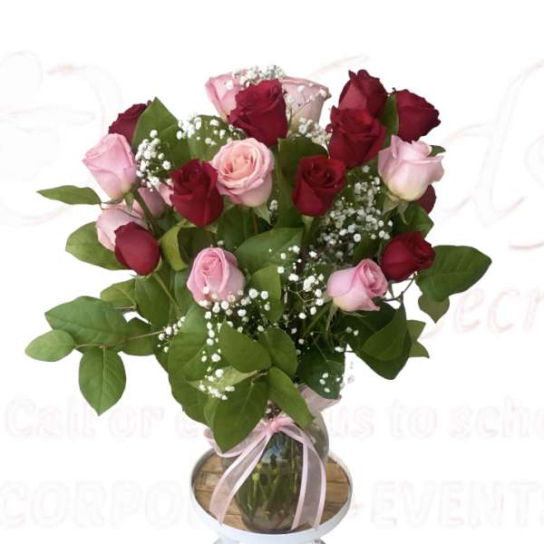 Bouquet of red and pink roses in a glass vase with a pink ribbon