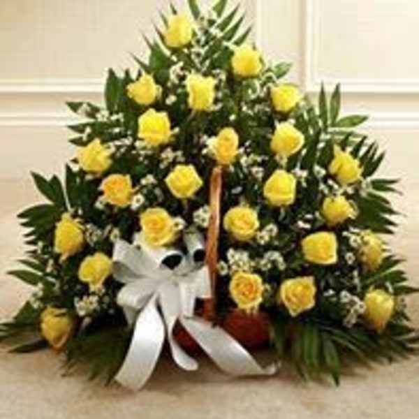 Yellow roses arranged in a basket with a white ribbon