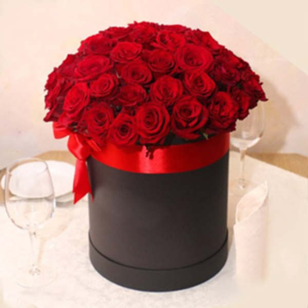 Red roses arranged in a black round box with a red ribbon
