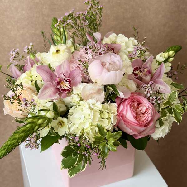 Pink and white floral arrangement in a pink box