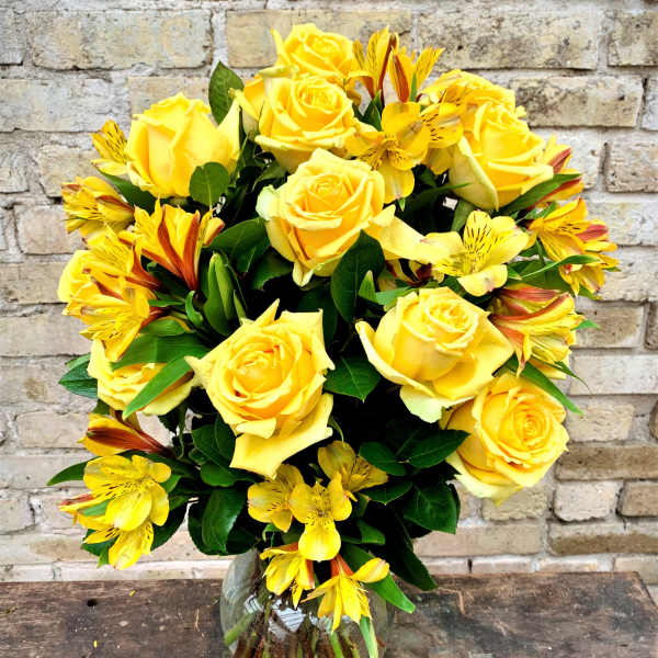 Yellow roses and yellow alstroemeria in a glass vase