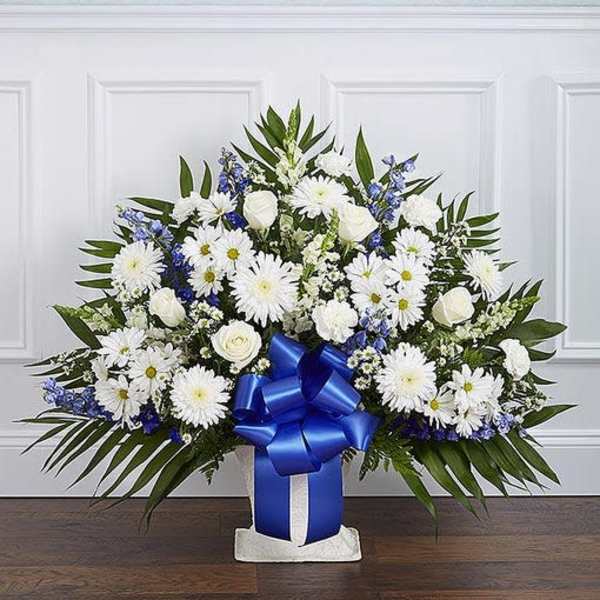 Tall white and blue floral arrangement with a large blue bow in a white container