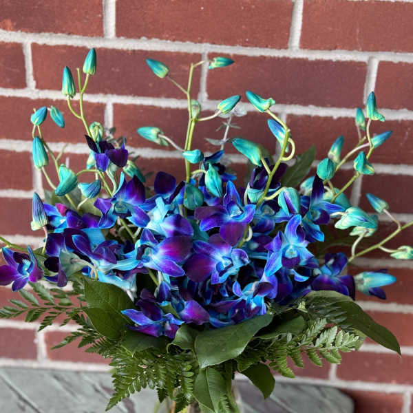 Blue and purple orchid bouquet in a clear glass vase