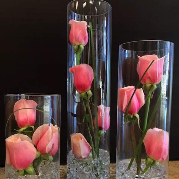 Pink roses arranged in three clear glass cylinder vases