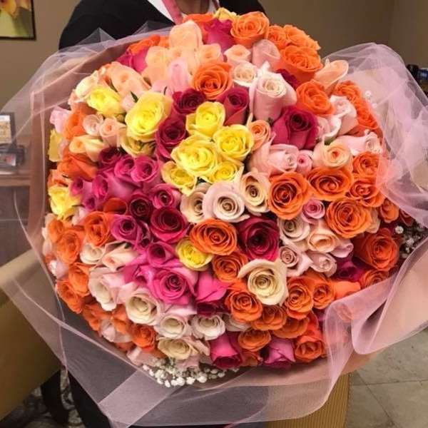 Large bouquet of multicolored roses wrapped in pink tulle