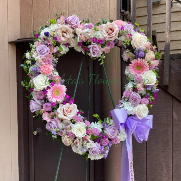 Heart-shaped floral wreath with pastel roses and gerbera daisies, tied with a lavender bow