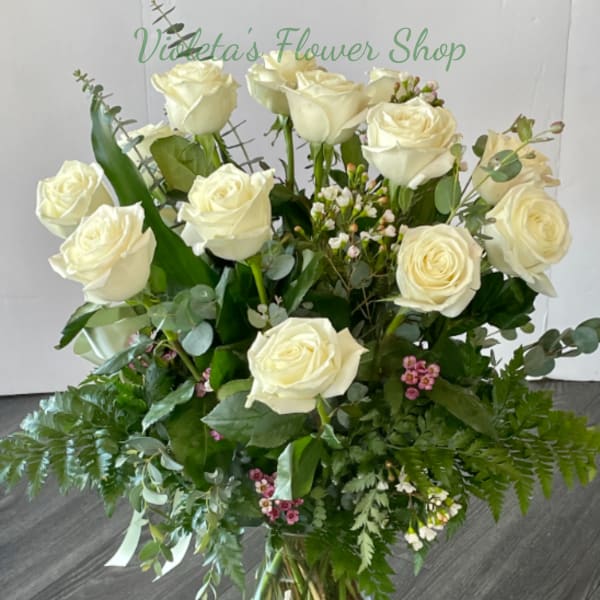 Bouquet of white roses in a clear glass vase with mixed greenery