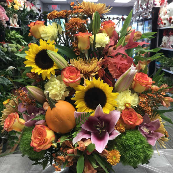 Colorful floral arrangement with sunflowers, roses, lilies, and a pumpkin