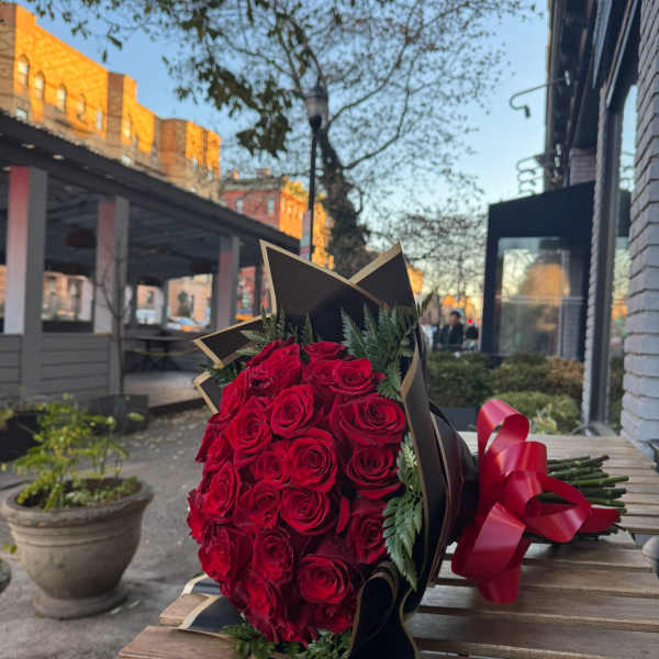 Bouquet of red roses wrapped in black paper with a red ribbon