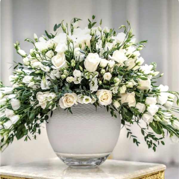 White floral arrangement in a glass vase on a gold table