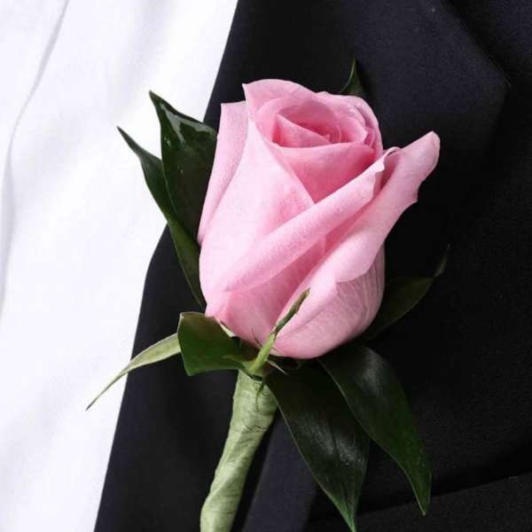 Pink rose boutonniere on a black suit jacket