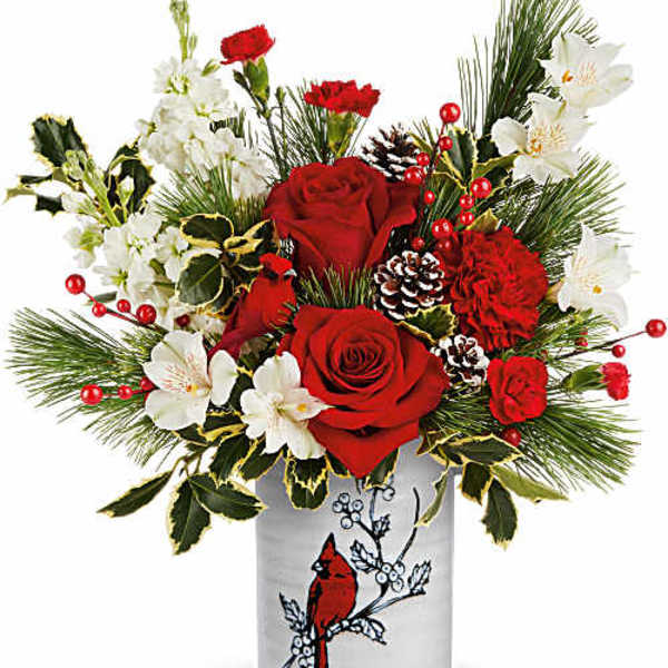 Red roses and white flowers in a decorative vase with pine accents