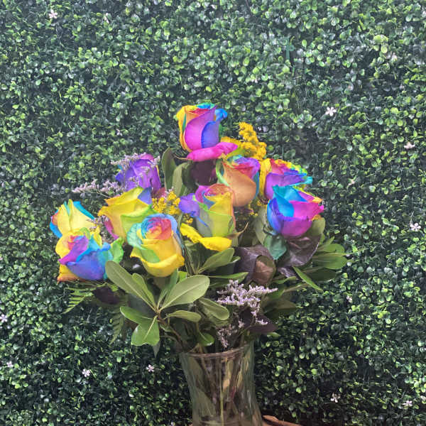 Rainbow-colored roses in a clear glass vase