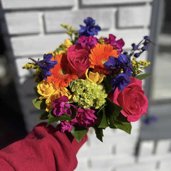 Handheld bouquet of bright mixed flowers with roses and gerberas