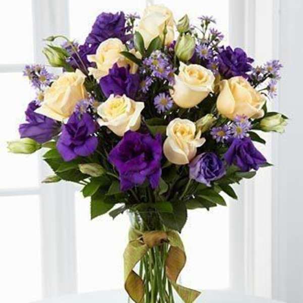 Bouquet of cream and purple roses in a clear glass vase