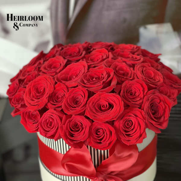 Red roses arranged in a round hat box with a red ribbon