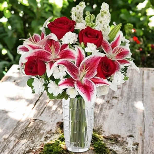 Red roses and pink lilies in a clear glass vase