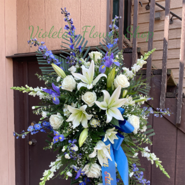Standing floral spray with white lilies, white roses, and blue flowers
