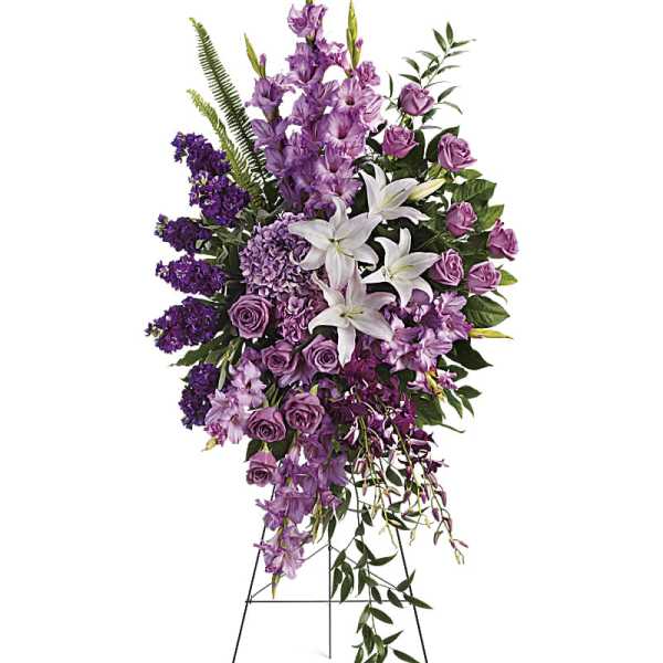 Tall standing spray of purple flowers and white lilies on a metal easel